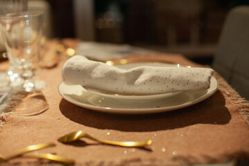 Festive christmas table setting with white and gold color plates, tableware, glasses and candles and holiday season decor.	