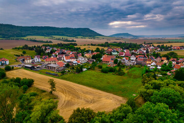 Fototapeta premium Aer ial view of a German village surrounded by meadows, farmland and forest in Germany.