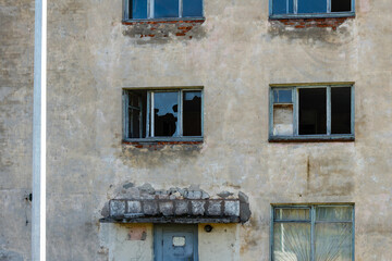 Naklejka na ściany i meble Close-up of a dilapidated wall of a house with broken windows after a bomb hit