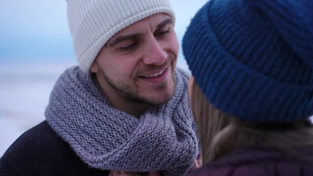 Headshot of handsome young man whispering on ear of woman smiling admiring partner. Close-up portrait of happy confident loving Caucasian boyfriend dating with girlfriend on winter day outdoors