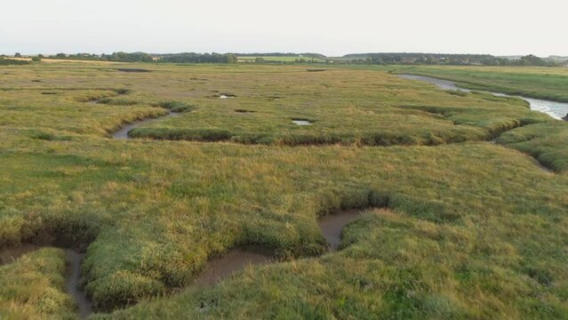 Low Aerial Drone Shot Flying Over Fairly Dry Green Salt Marsh at Sunset in North Norfolk UK