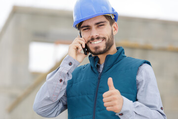 happy male builder on the phone showing thumb up