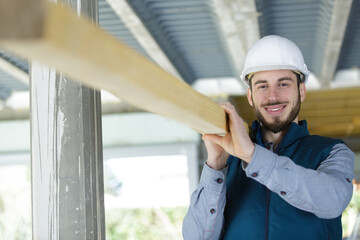 carpenter carrying timber plank at construction site