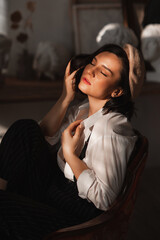 beautiful brunette woman in an armchair in the rays of the sun from the window.