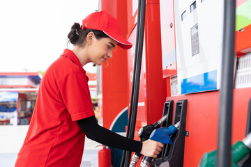 Attendant service female worker refuelling car at gas station. Assistant woman worker wear red...