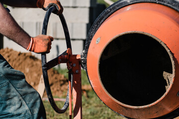 Bricklayer preparing concrete with a cement mixer to build a wall at a construction site