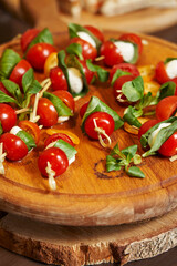 cherry tomatoes with mozzarella on skewers on a wooden tray. delicious diet snack. anipasti