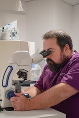 Veterinarian in the laboratory looking at samples through the microscope.