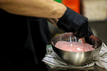 pastry chef preparing white chocolate pink filling for piping bag for frosted dripping cake...