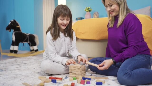 Mom and cute little girl playing together, brain teasers. Happy little girl and mother.