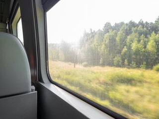 View from the window of a modern train on a sunny summer day. Traveling by rail in a comfortable...