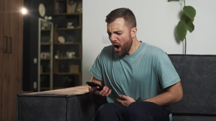 Portrait of a young man suffering from a sharp stomach ache while sitting on a sofa