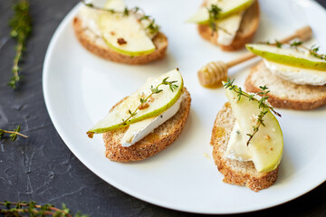 Sandwich or bruschetta with pear and blue cheese on white plate on black background, copy space.
