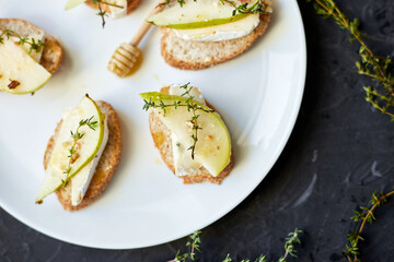 Sandwich or bruschetta with pear and blue cheese on white plate on black background, copy space.
