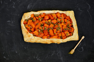 Delicious open pumpkin pie on black background with honey and thyme, space for text.