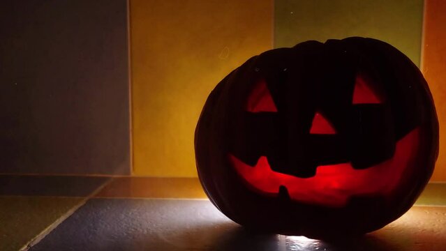 A Halloween pumpkin glowing inside in the dark.