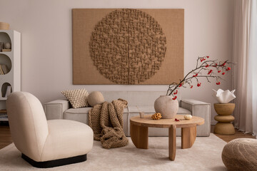 Creative composition of living room interior with mock up poster frame, beige sofa, wooden coffee table, rounded shapes armchair, vase with rowanberry and personal accessories. Home decor. Template..