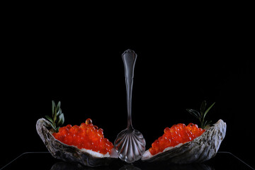 Caviar spoon and red caviar in oyster shells. Serving snacks with red caviar. A symbol of wealth. A...