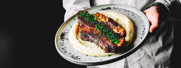 chef holding a Beef brisket slice and mashed potato in hand