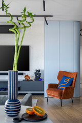 Interior design of living room interior with big tv, orange armchair, patterned pillow, wooden...