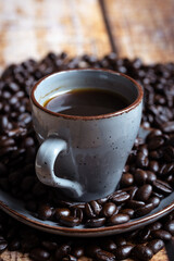 a cup of coffee with roasted beans on a wooden background, photographed from the front