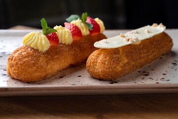 Eclair made with cream and hazelnut in plate on a wooden table. Healthy food