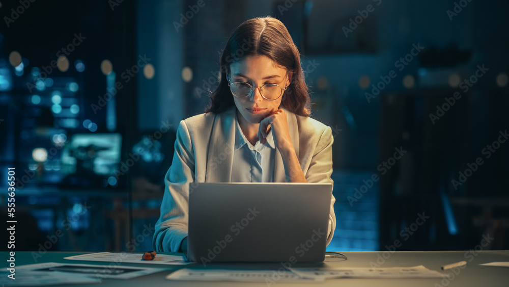 Poster beautiful female working on laptop computer in a company office at night. young secretary analyzing 
