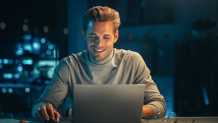 Portrait of a Stylish Male Working on Laptop Computer in a Company Office in the Evening. Young...