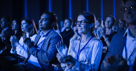 Young Woman Sitting in a Crowded Audience at a Business Conference. Female Attendee Cheering and...