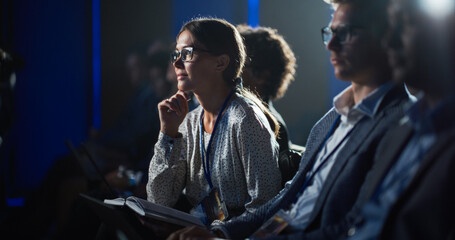 Young Enthusiastic Female Attending a Motivational Speaker Event, Sitting in a Crowded Concert...