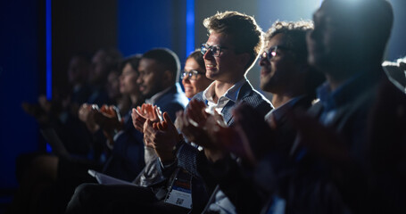 Young Male Sitting in a Crowded Audience at a Science Conference. Delegate Cheering and Applauding After an Inspirational Keynote Speech. Auditorium with Young Successful Specialist. - obrazy, fototapety, plakaty