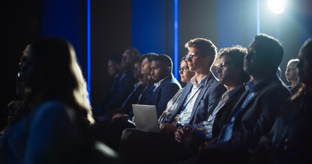 Handsome Man Sitting in a Crowded Audience at a Business Conference. Corporate Delegate Watching...