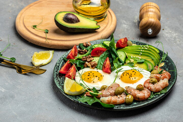 shrimps, prawns, soft fried egg, fresh salad, tomatoes, cucumbers and avocado on a light background. Ketogenic diet breakfast. Keto, paleo lunch. Top view
