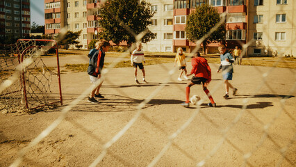 Young Multiethnic Boys and Girls Playing Soccer in the Neighborhood. Happy Multicultural Kids Playing Keep-Ups, Juggling and Controlling the Ball in the Air. Concept of Sports, Childhood, Friendship.