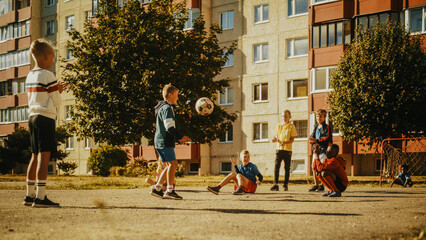 Young Multiethnic Kids Playing with Ball in the Neighborhood. Young Boy Practicing Soccer Drills, Controlling the Ball in the Air. Friends are Clapping and Cheering for Him.