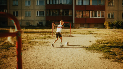 Young Caucasian Kid Playing with Ball in the Neighborhood. Young Boy Practicing Soccer Drills, Doing Kick-Ups. Teenager Dreaming of Becoming a Professional Football Player.
