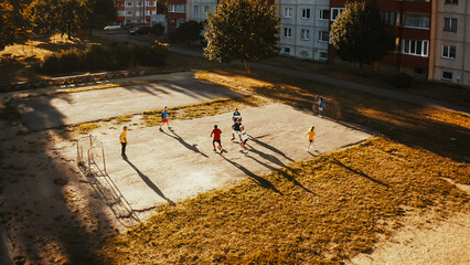 Aerial Drone Shot of Neighborhood Friends Playing Soccer Outside in Urban Backyard. Multicultural Kids Play Football Together in the Suburbs. Happy Childhood and Sports Concept.