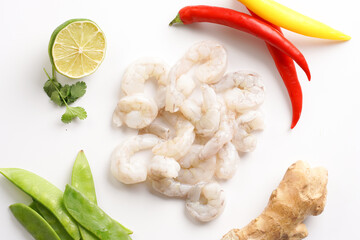 Ingredients for a spicy thai coconut soup or curry: cherry tomatoes, snow pea, chili pepper, lime, ginger, shrimps and fresh cilantro