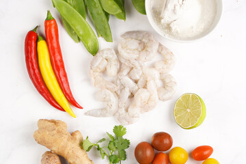 Ingredients for a spicy thai coconut soup or curry: coconut milk, cherry tomatoes, snow pea, chili...