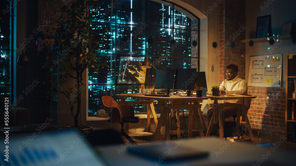 Leinwandbilder focused project manager sitting at a desk, working alone on a computer in an office at night. black 
