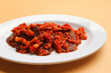 Dendeng balado or jerky beef with spicy seasoning is a traditional cuisine from west sumatera, indonesia. it is made from slice of beef with spicy sauce called sambal. served on plate.