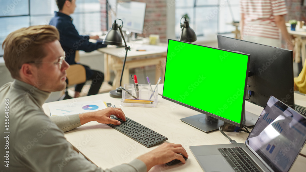Aufkleber Portrait of Young White Man wearing Glasses Working on Laptop and Green Screen Computer During Day in Modern Bright Office. Business Man Using Chroma Key on Personal Computer.