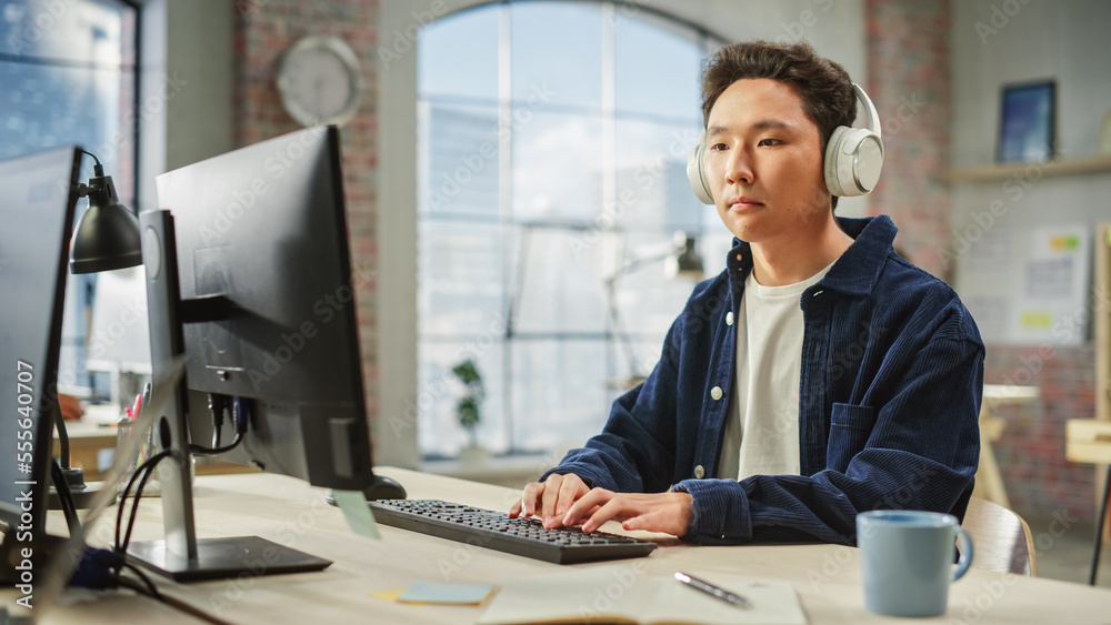 Poster portrait of asian male employee working on computer in a modern office during the day. customer supp