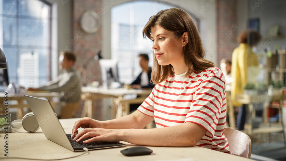 Poster portrait of caucasian woman typing on a laptop at work in a spacious modern office. female operation