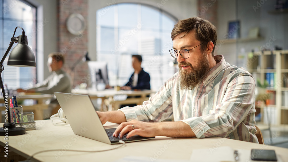 Leinwandbilder portrait of caucasian young man working on a laptop in a spacious bright office. male sales represen