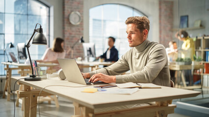 Portrait of White Focused man Using Laptop in a Contemporary Spacious Office. Account Specialist Focused While Having Productive Day. Active Colleagues Working on Computers in the Background.