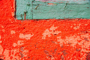 un mur crépi en rouge et du bois peint en vert. Un mur rouge graphique et une pointe de vert.