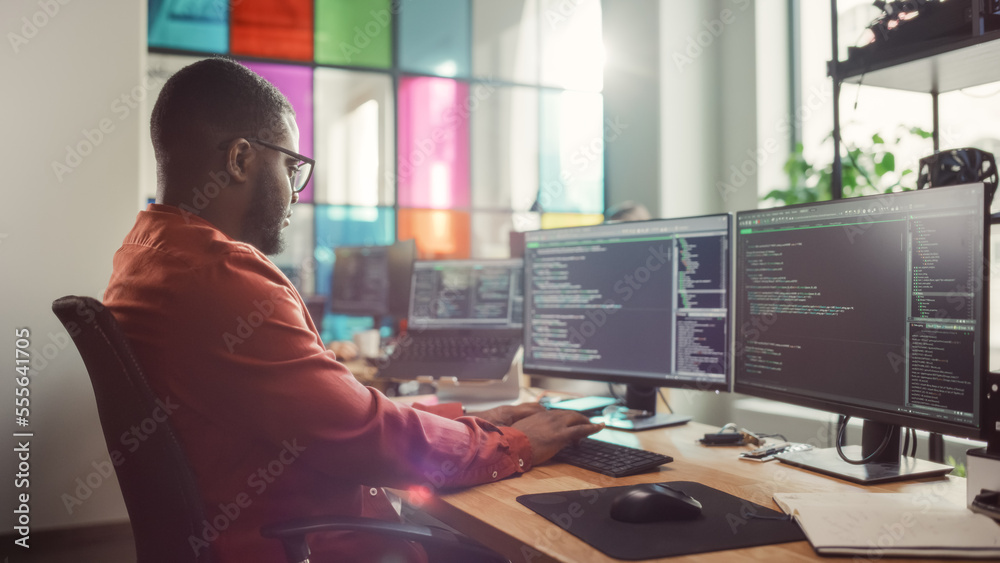 Poster African American Man Coding on Desktop Computer with Professional Multiple Monitors Setup in Creative Office. Male Software Engineer Developing Mobile Application for Innovative Start-Up.