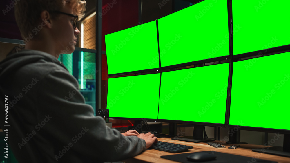 Poster young caucasian man writing code on professional six monitors setup with green screen chromakey. mal
