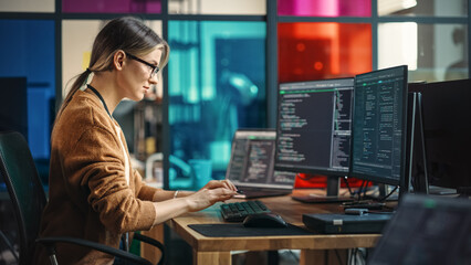 Young Caucasian Woman Programming On Desktop Computer With Two Monitors Setup in Spacious Office. Female Software Developer Creating SaaS Platform For Businesses in Innovative Start-up Company. - obrazy, fototapety, plakaty